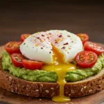 Close-up of creamy avocado toast with poached egg, cherry tomatoes, and chili flakes on whole grain bread.